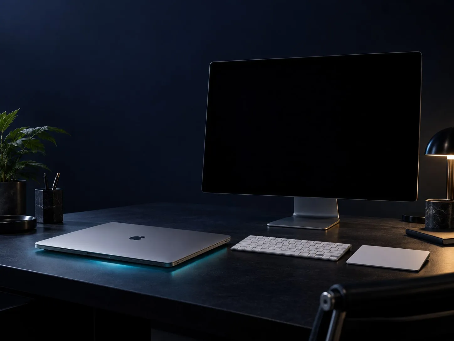 A closed MacBook beside a dark external monitor, illustrating Screens off mode while background work continues